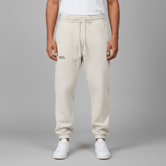 Model wearing SOL Nomad Fleece Joggers in Mild Apricot, showing the front logo, drawstring waist and gathered cuffs.
